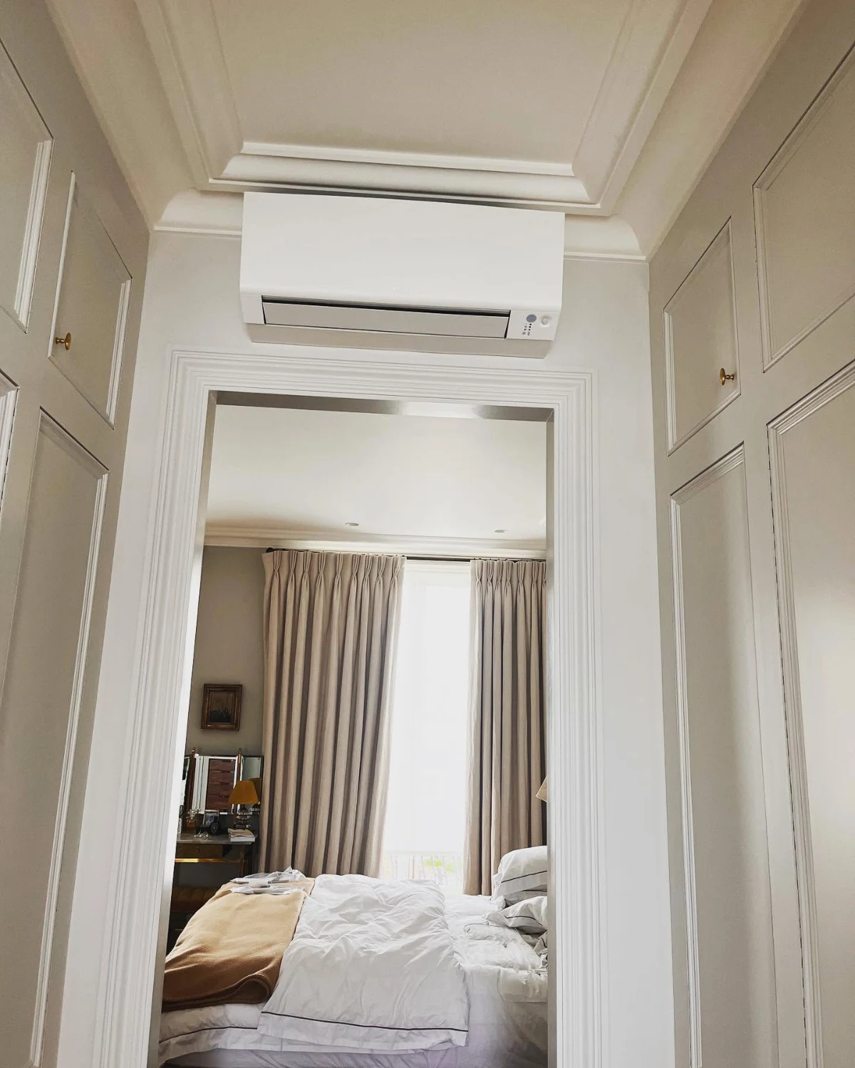 Wall-mounted air conditioning above a bedroom doorway in a period London home