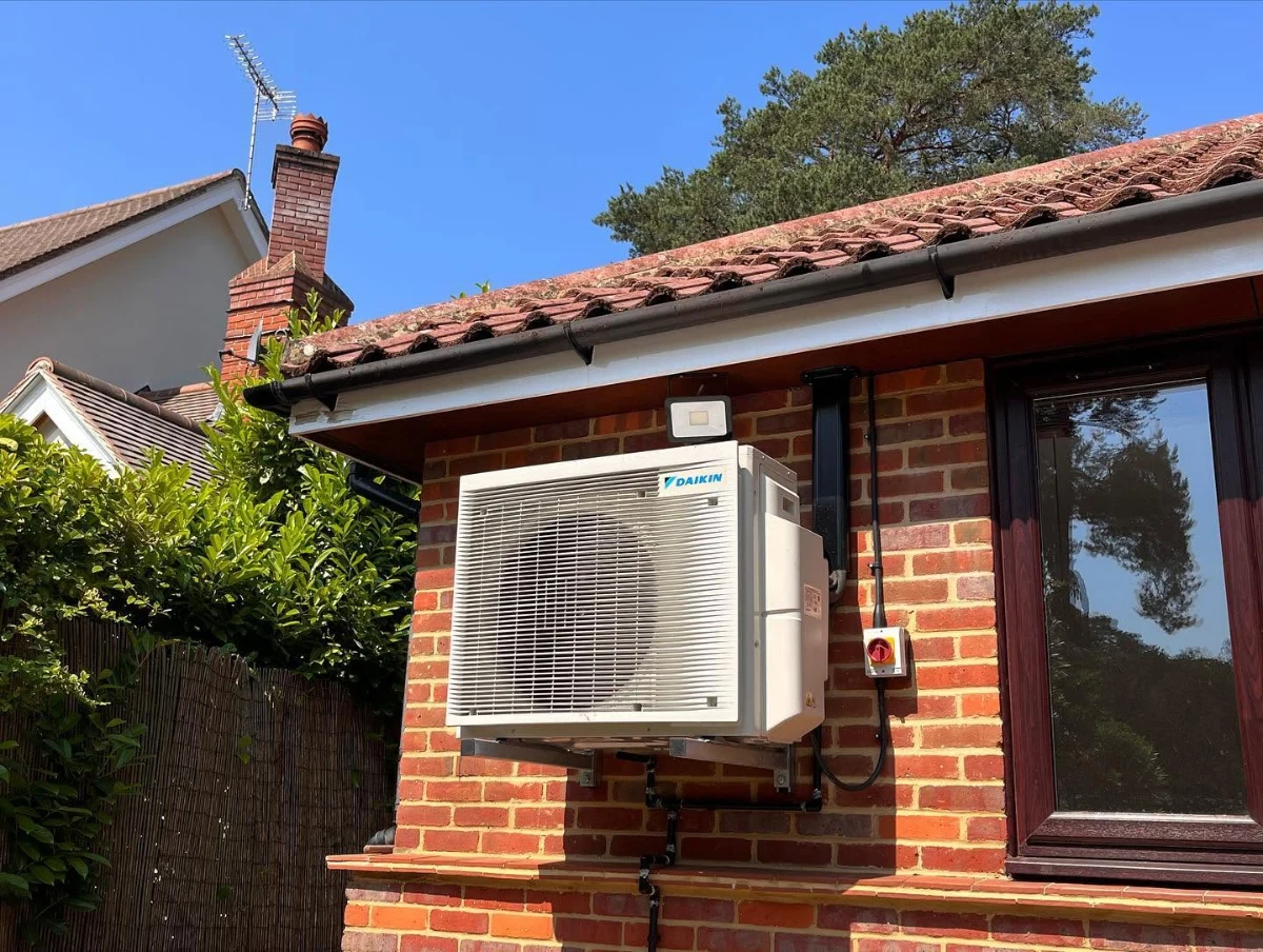Wall-mounted outdoor condenser unit on a bungalow with tidy pipework